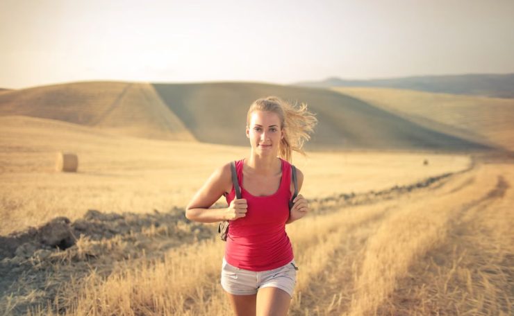 A woman jogging through vast, golden wheat fields under the summer sun, symbolizing freedom and adventure.