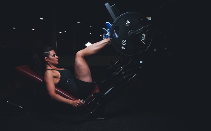 A woman engages in an intense leg press workout at the gym, showcasing strength and fitness.